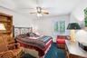 Bedroom with ceiling fan, dark colored carpet, and a desk