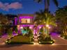 Front elevation at night showcasing stone facade, paver entry walkway, bronze sculpture, manicured hedges, motor court, illuminated reflecting pools,