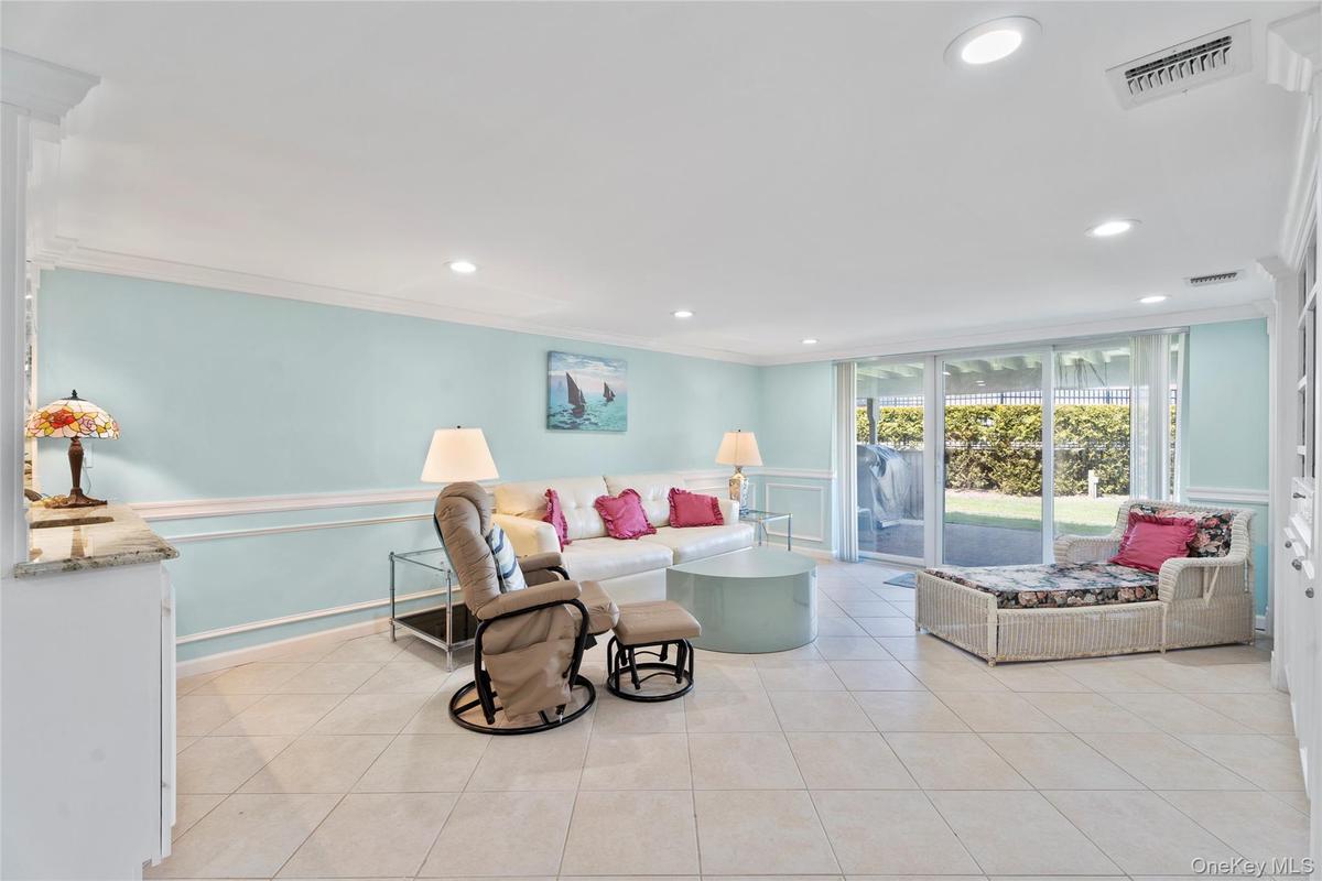 Living area with visible vents, a decorative wall, light tile patterned floors, and crown molding