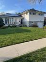 White siding exterior with a stone veneer accent, bay window, solar panels, and attached garage