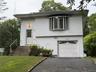 Exterior featuring white horizontal siding, a bay window with multiple panes, a white garage door with decorative lites, and a paved driveway