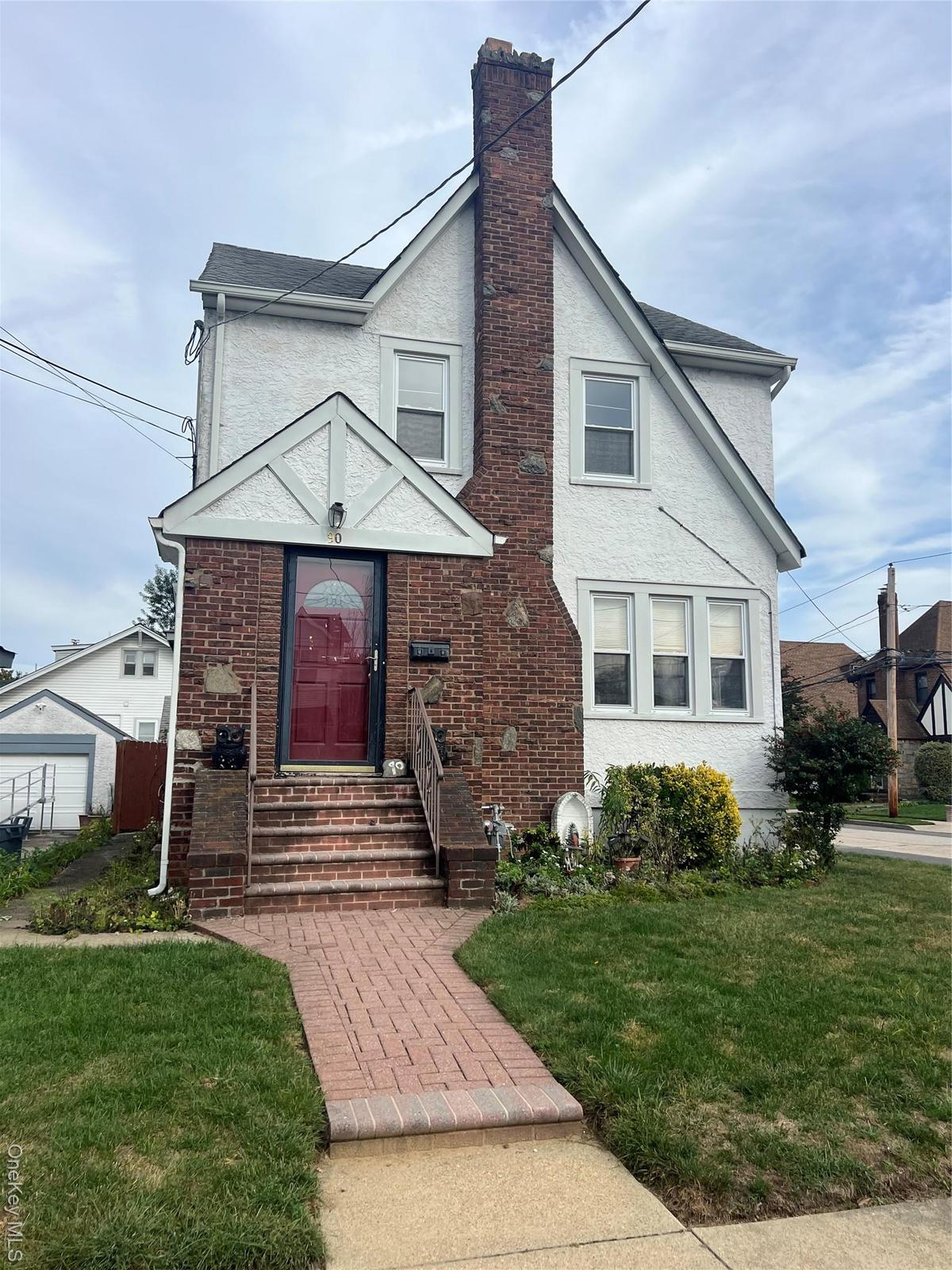 View of front of property with a front lawn, a chimney, and stucco siding