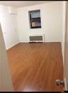 Empty room with dark wood-style floors and radiator heating unit