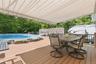 Expansive outdoor entertaining area featuring a wood-finish deck, an above-ground swimming pool, and a white canvas awning