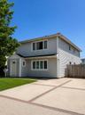 Two-story residence featuring light gray siding, white trim, and large private driveway.