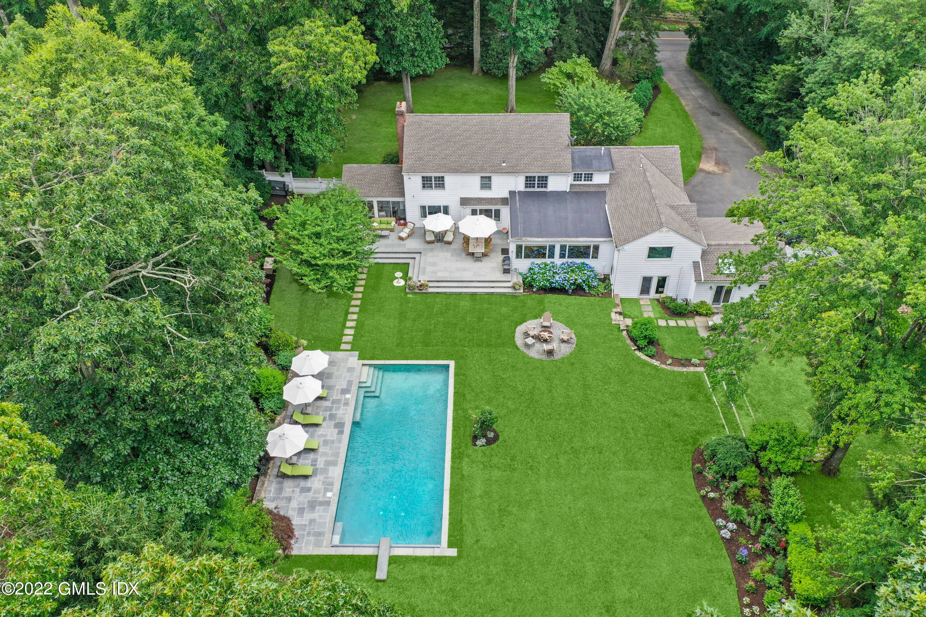 Private backyard retreat with pool, stone terrace, fenced in yard and stylish six bedroom Colonial set back on two Mid Country acres.