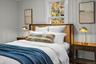 Warm and inviting bedroom accented by custom wall paneling, updated lighting, and peaceful treetop views.