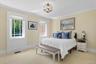 Carpeted bedroom with multiple windows, crown molding, and a chandelier