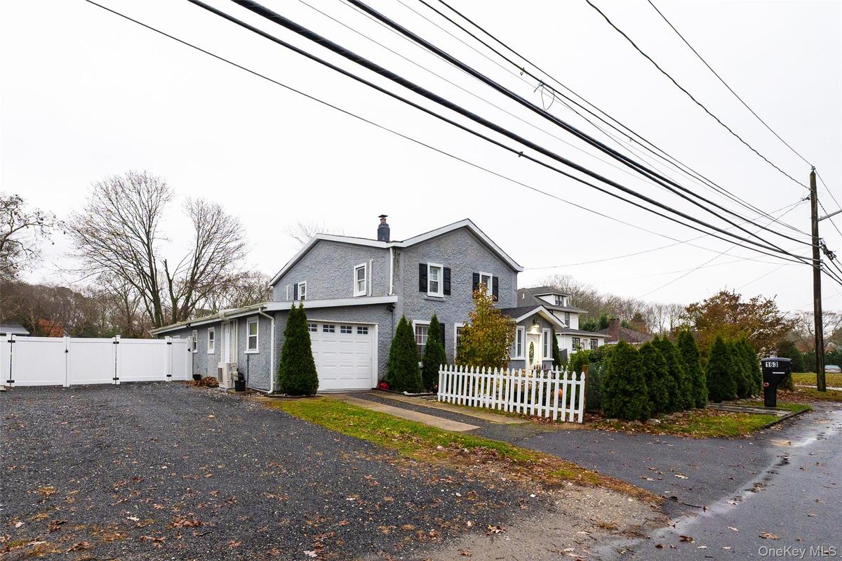 View of side of home featuring a gate, a chimney, driveway, and an attached garage