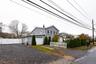 View of side of home featuring a gate, a chimney, driveway, and an attached garage