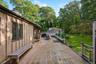 Wooden deck featuring a lawn, outdoor dining area, and view of wooded area