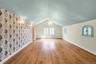 Spacious interior featuring 2 Parrett windows, wood-finish flooring, a vaulted ceiling, wall sconces and a decorative chandelier
