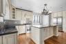 Kitchen with cream cabinetry, a center island, custom range hood, high end appliances, and sink