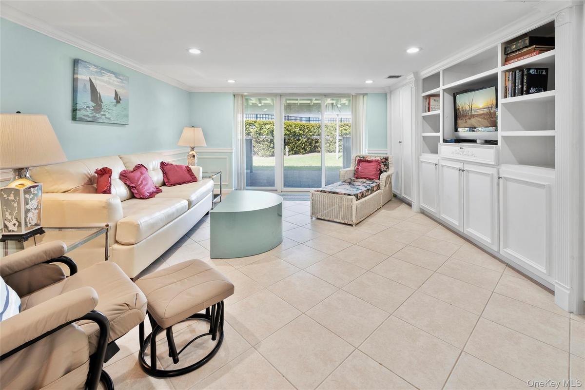 Living room with recessed lighting, built in shelves, light tile patterned floors, and crown molding