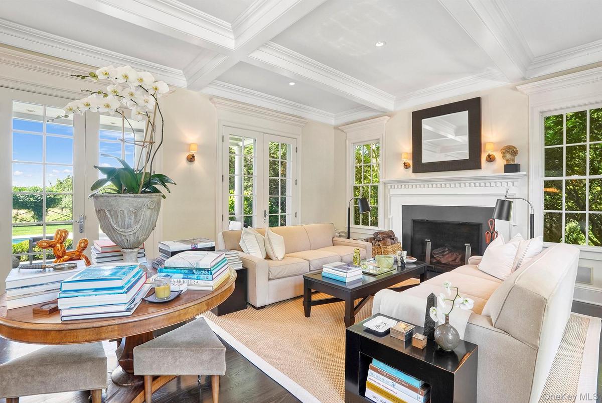 Living room with beamed ceiling, plenty of natural light, coffered ceiling, ornamental molding, and a fireplace