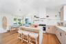 Kitchen featuring open shelves, a kitchen bar, pendant lighting, range with gas stovetop, and decorative backsplash