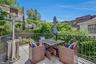Outdoor patio space with black ornamental railing, paver flooring, and abundant perimeter greenery