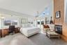 Bedroom featuring light carpet, a tile fireplace, high vaulted ceiling, and multiple windows