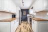 Renovated kitchen featuring white cabinetry, wood-finish flooring, and stone countertops
