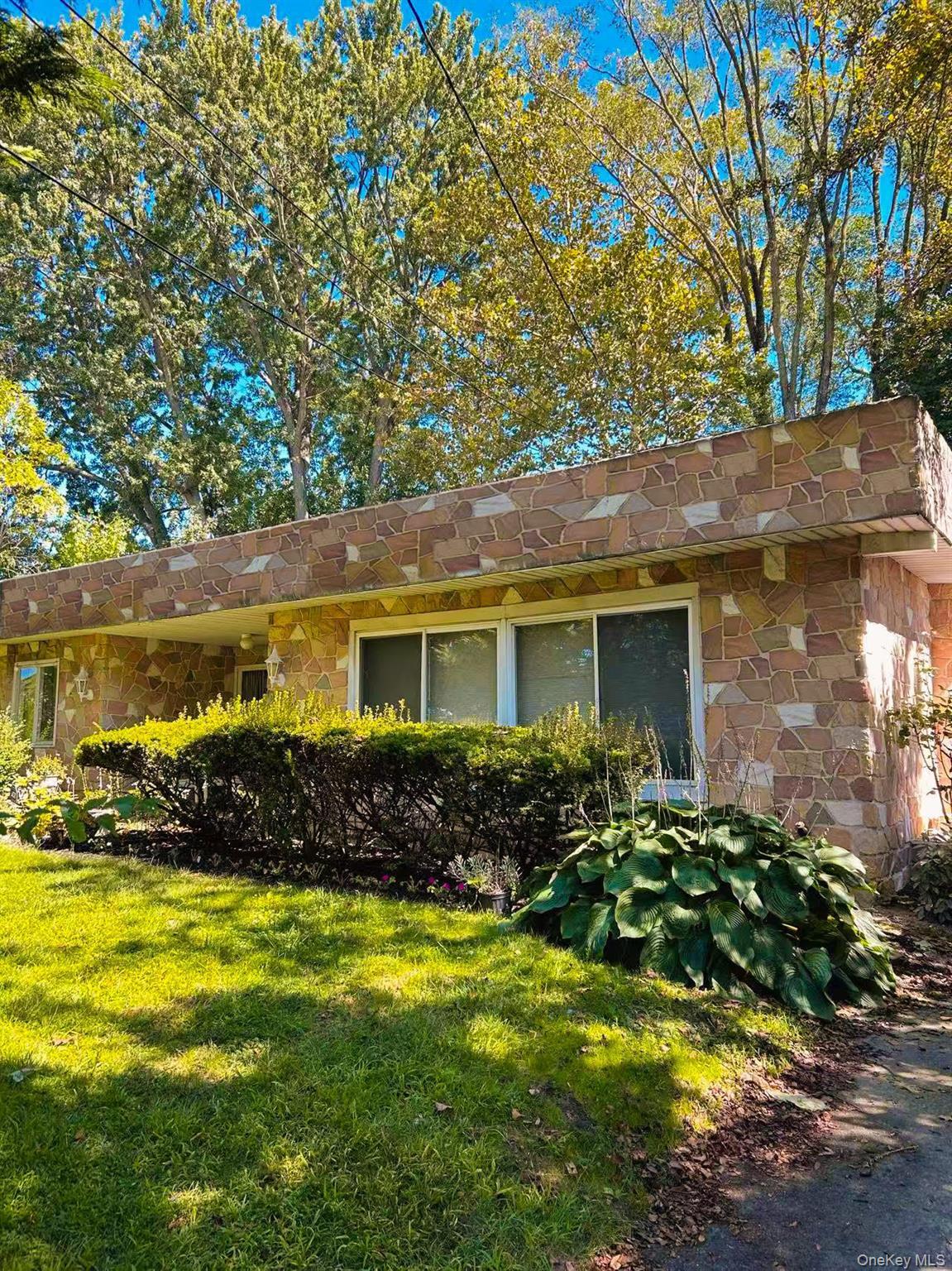 View of property exterior featuring stone siding and a lawn