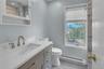 Bathroom featuring a baseboard radiator, vanity, and a marble finish shower