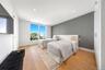 Bedroom with wallpapered walls, an accent wall, and light wood-style floors