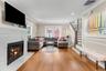 Spacious interior featuring wood-finish flooring, a white stacked stone fireplace, and crown molding, recessed lighting.
