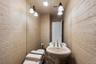 Pedestal sink with chrome fixtures and overhead vanity lighting