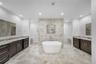 Bathroom with a freestanding tub, two vanities, recessed lighting, tile walls, and walk in shower