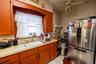 Kitchen featuring freestanding refrigerator, light countertops, a ceiling fan, light tile patterned flooring, and open shelves