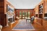 Office space featuring wood walls, built in features, ornamental molding, a high end fireplace, and light wood-style flooring