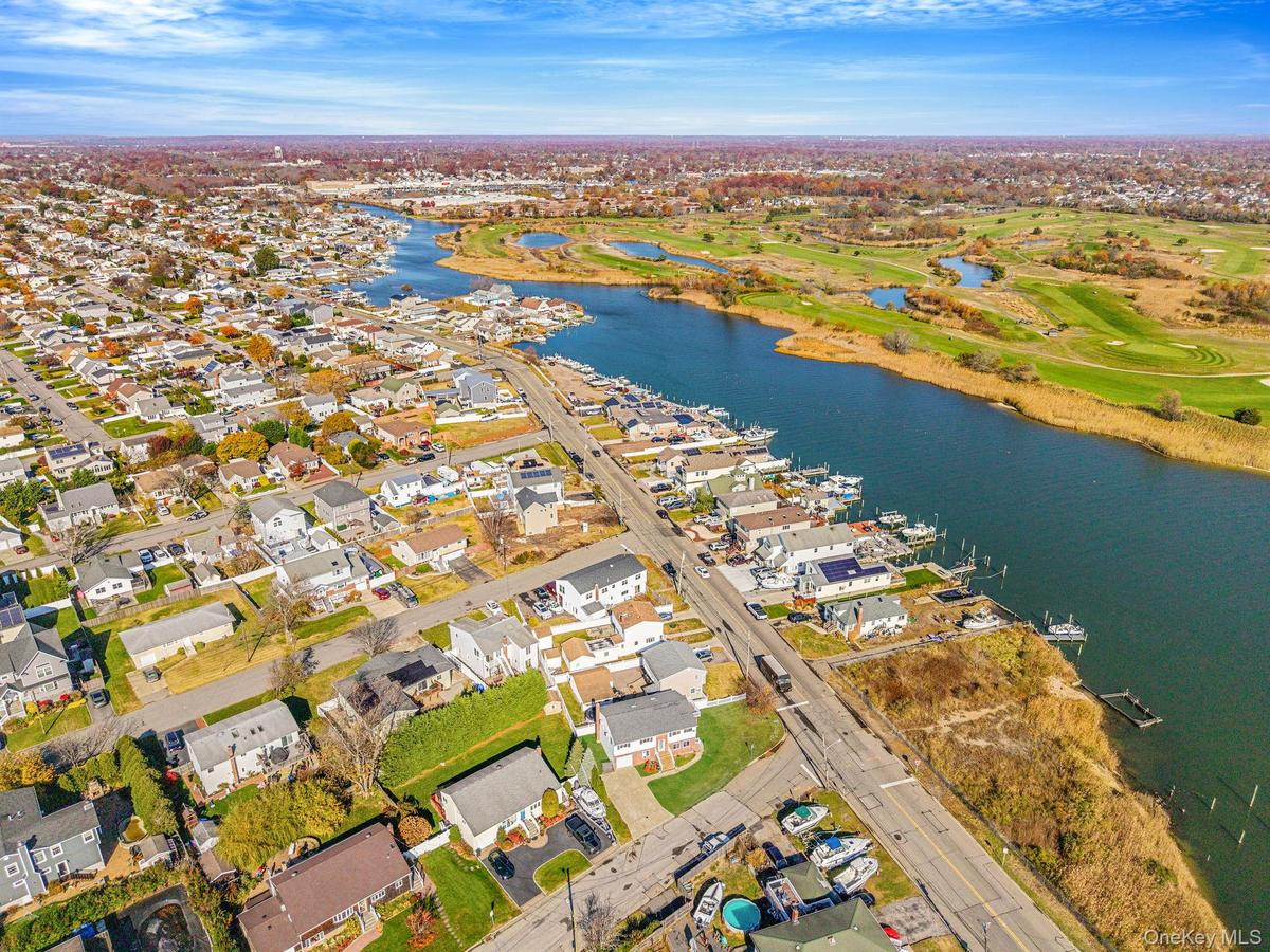 Aerial view of property and surrounding area with nearby suburban area, a nearby body of water, and a golf course